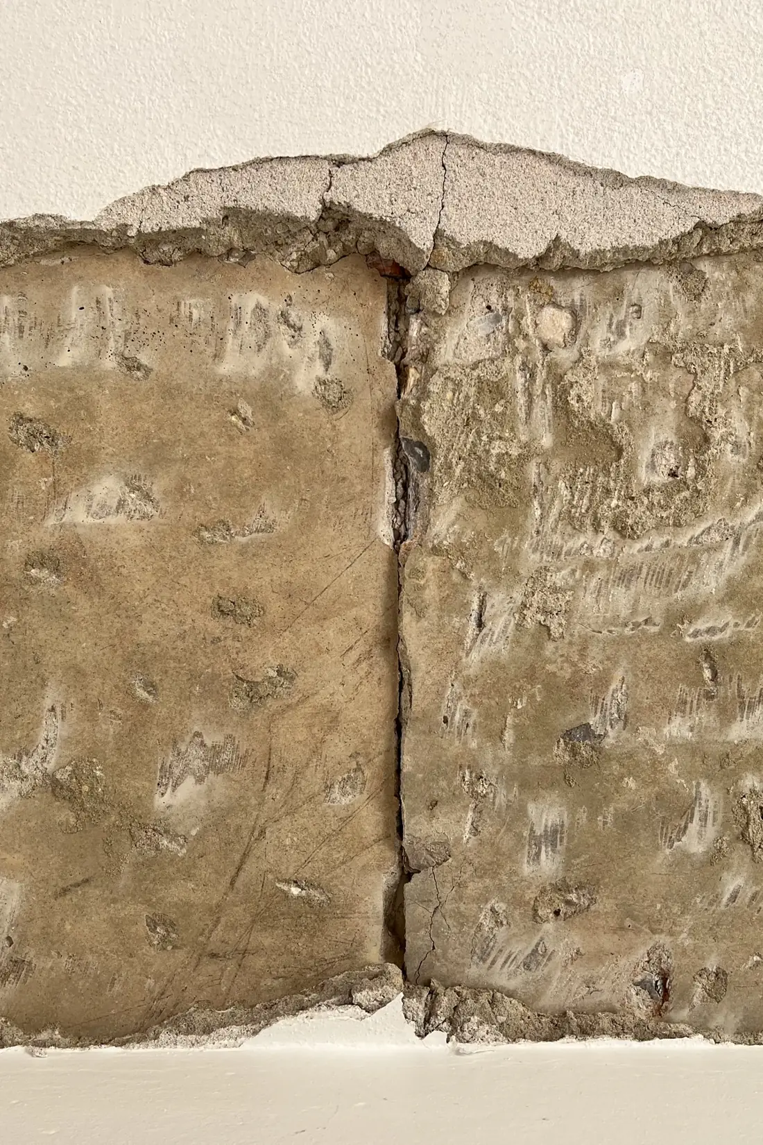 A wall detail with a strip of finish removed, bounded by finish above and below, and a dark vertical line crossing the exposed area.