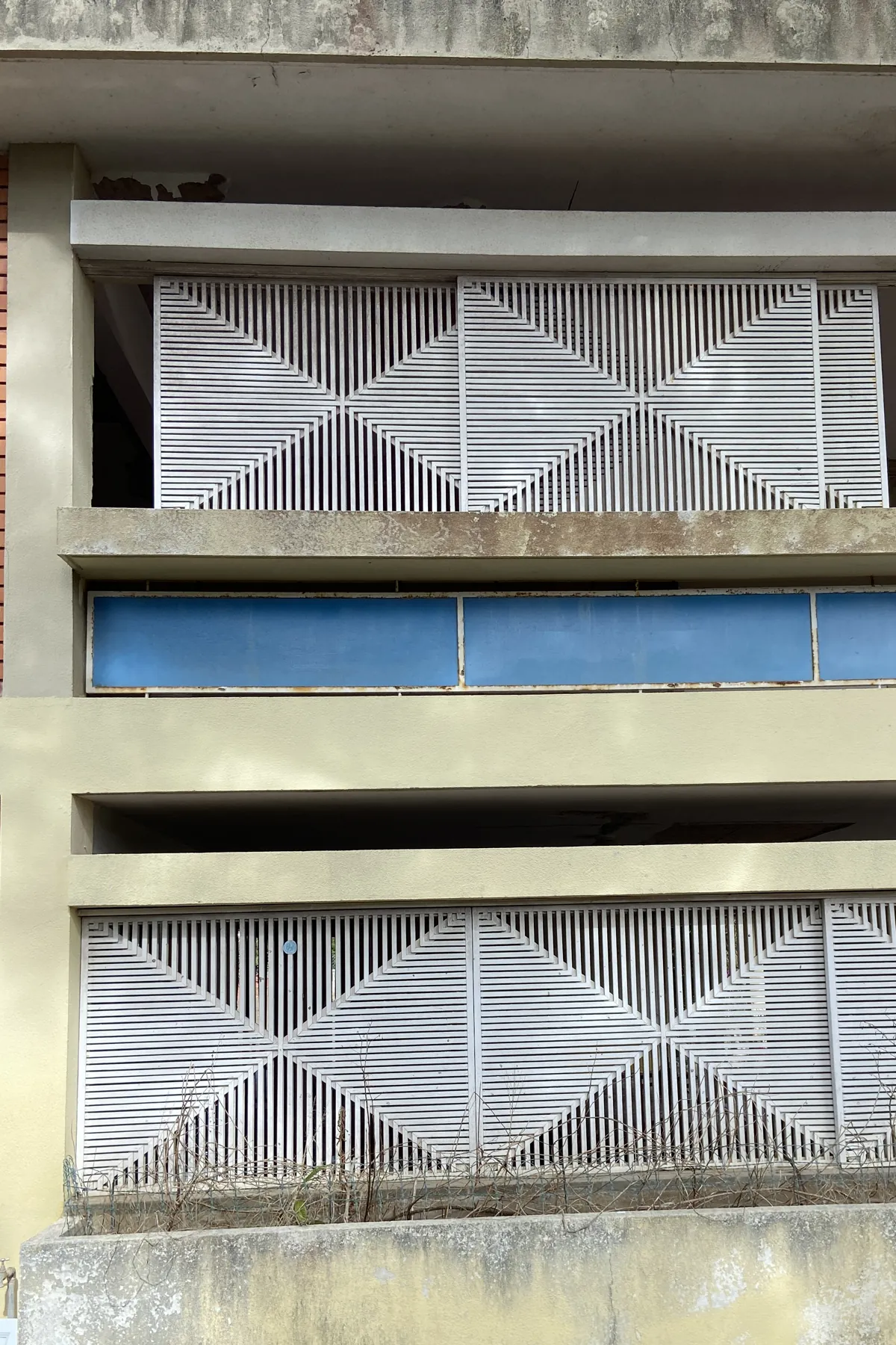 The garden elevation in close-up: two bands of white screen panels with a diamond pattern, between pale horizontal bands, with a brick panel at one side and a blue band between the floors.