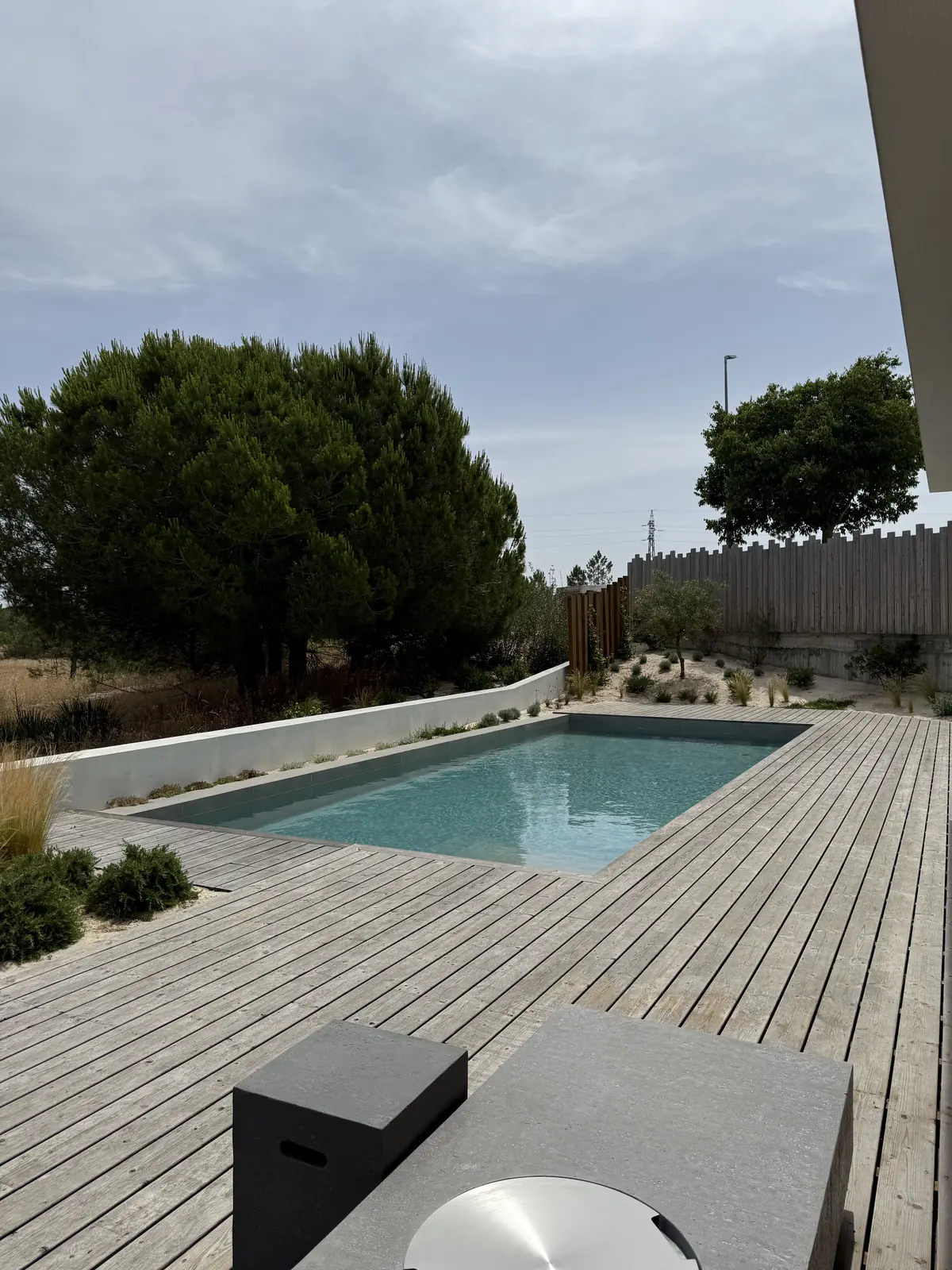 A finished pool and timber deck with outdoor furniture, seen past the eaves of the house.