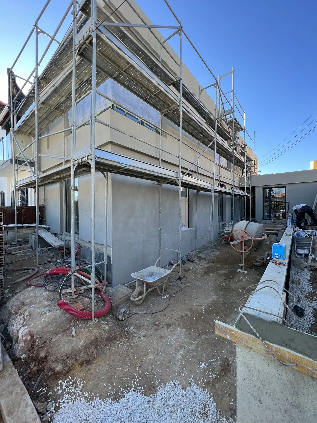 A concrete frame of several levels under scaffolding, with the site cleared around it.