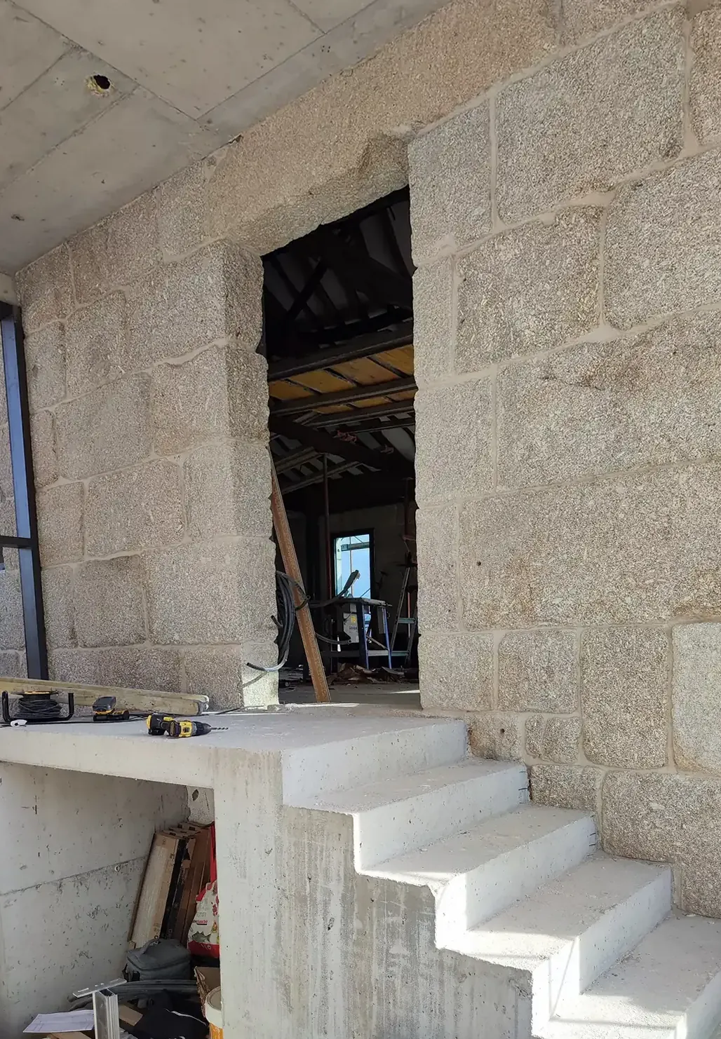 A white concrete stair rising against a wall of large granite blocks.