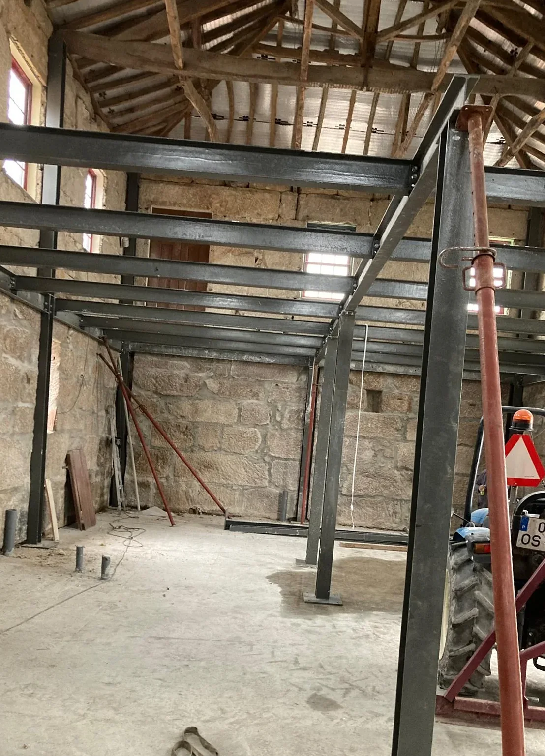 Steel beams and columns inserted inside a granite shell, seating on the masonry, with the original timber roof structure above them.