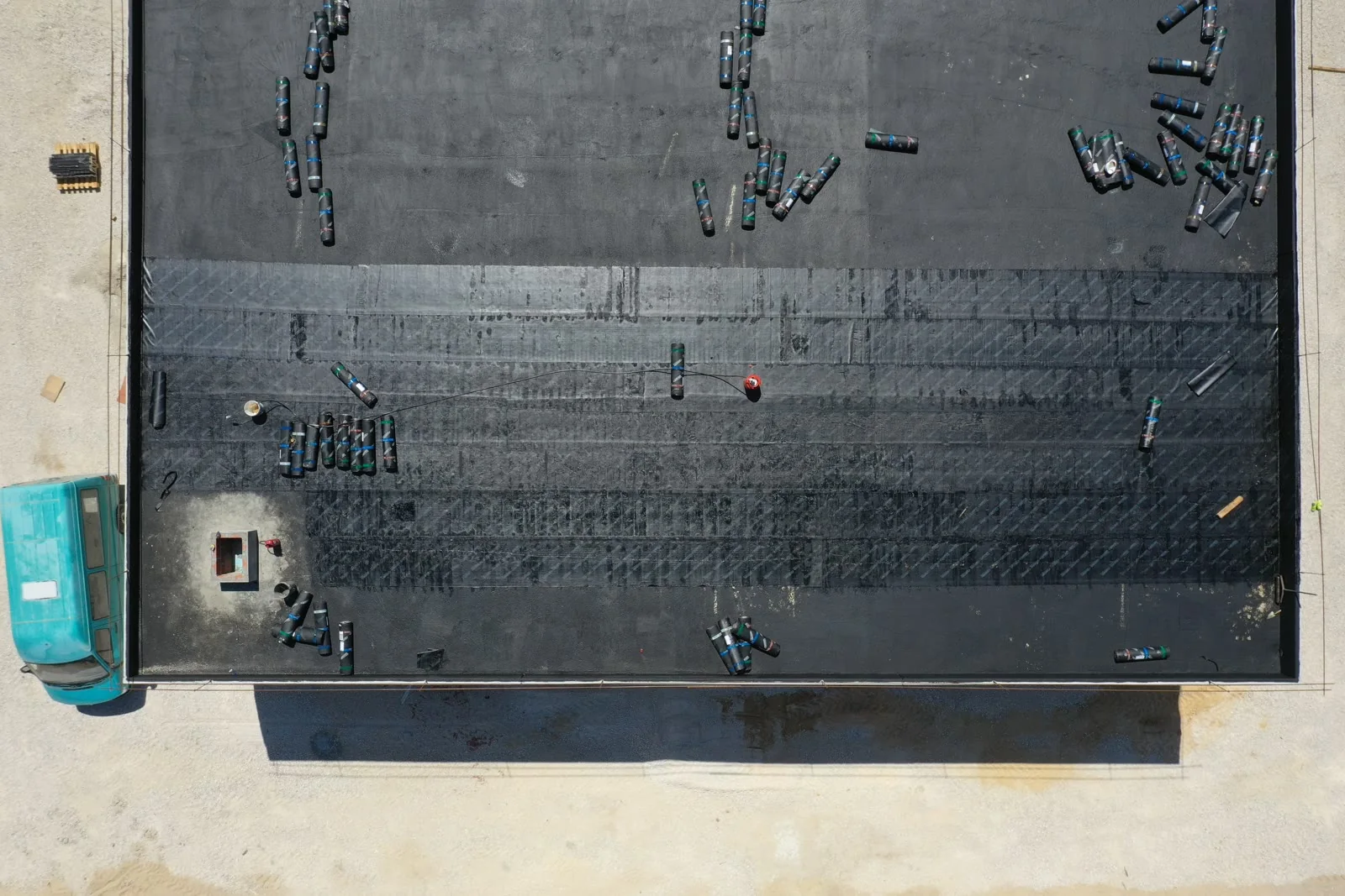 A near-vertical aerial view of a large roof slab under construction, reinforcement laid out across it and services set into it before the pour.