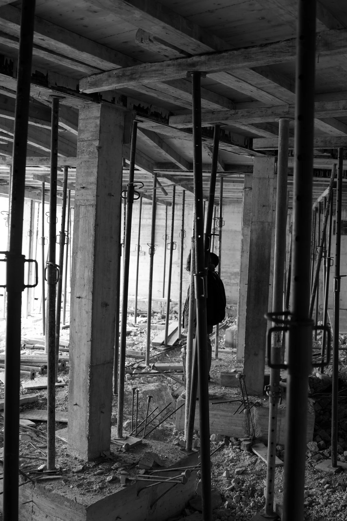 Black and white: a floor under a dense array of metal uprights, with vertical elements receding into the distance.