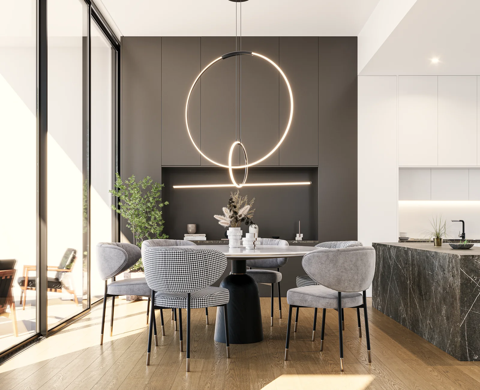 A dining table under a circular pendant beside a dark stone kitchen island.