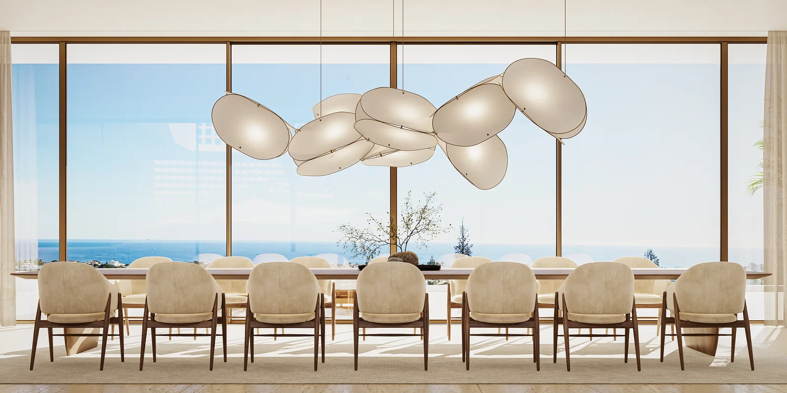 The dining room seen head on: a long table for twelve against an uninterrupted wall of glass, a cluster of pale sculptural pendants above it and the ocean filling the whole opening.