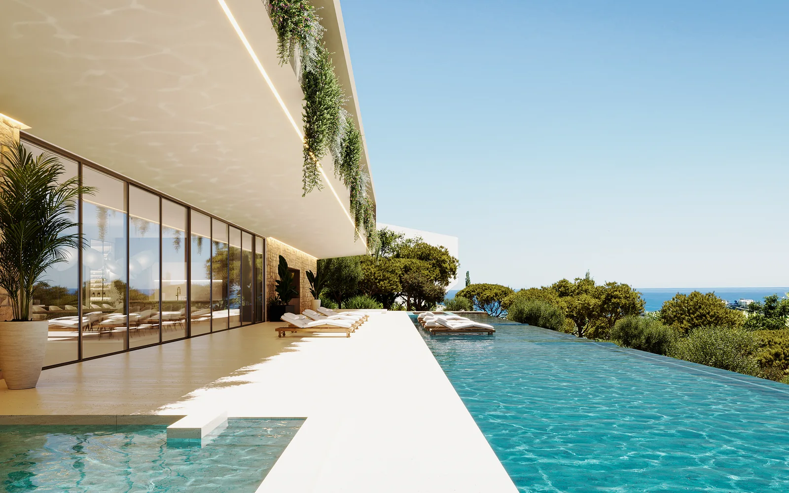 A long infinity pool running the length of the house towards the sea, the water meeting the horizon, with loungers on the stone deck and a planted upper edge above the glazing.