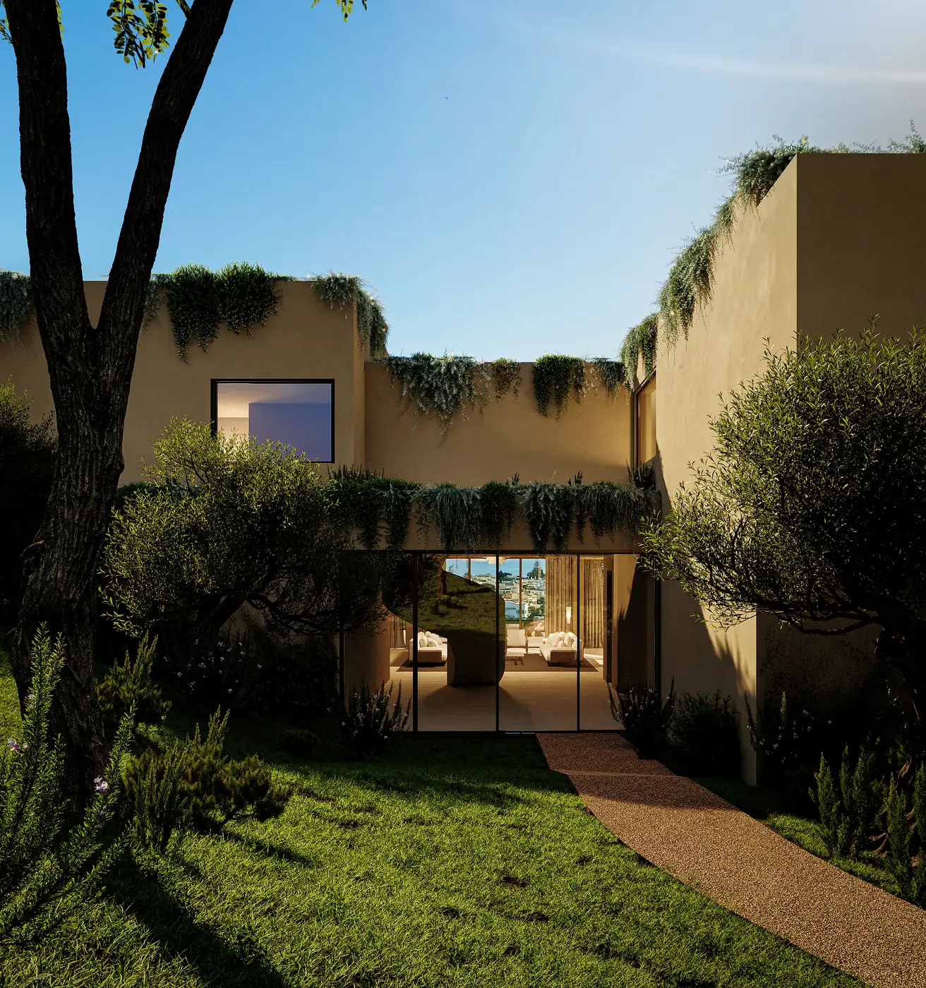 The entrance courtyard from the garden side, framed by a mature tree, with lawn running up to the threshold and the interior lit beyond the opening.