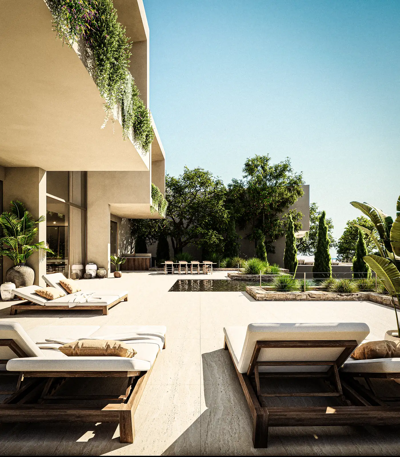 The pool terrace along the flank of the house, loungers in a row on pale paving, cypresses and olive against the render, and the upper floor overhanging in shade.