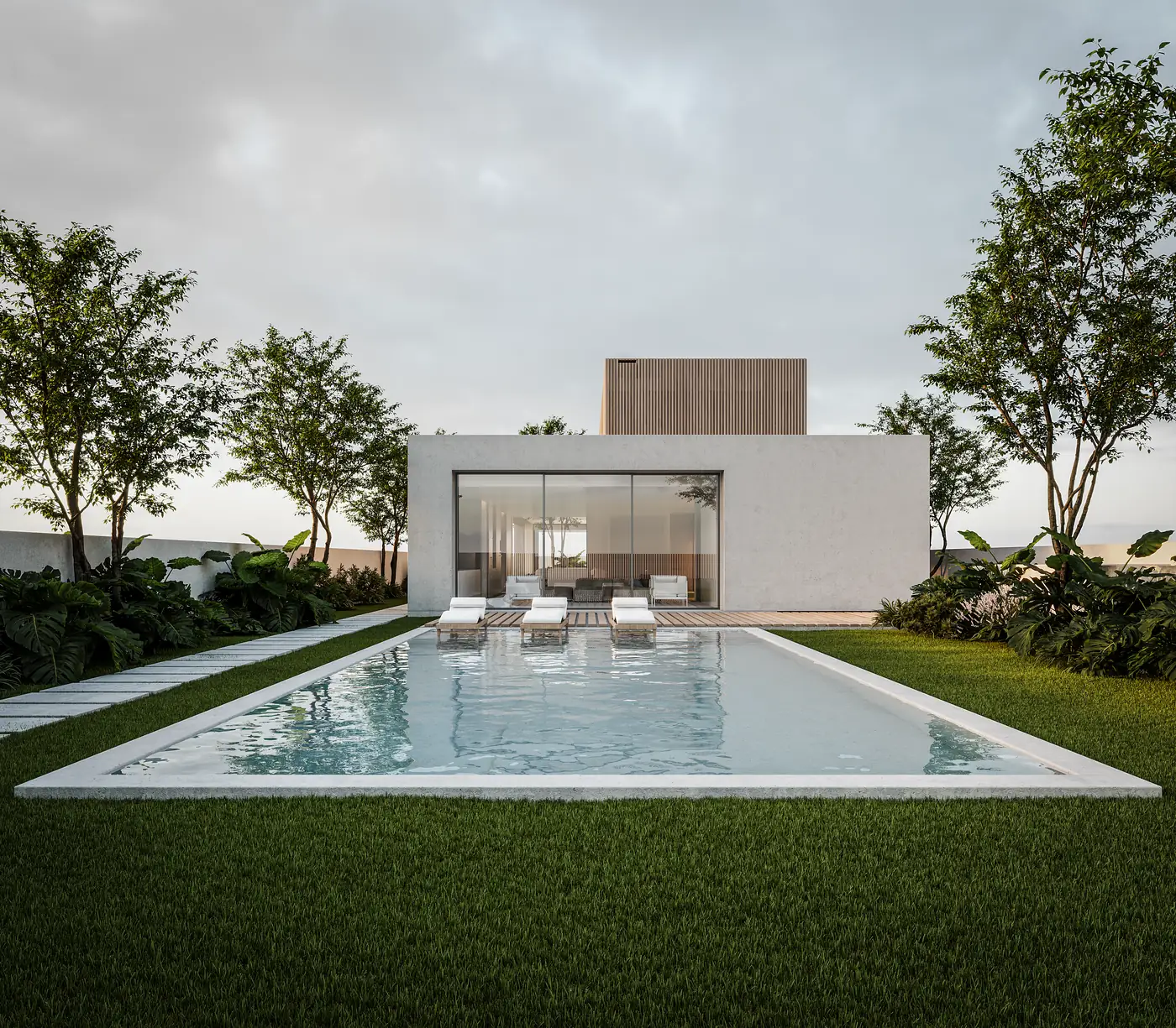 A casa vista do topo do jardim: uma piscina alongada sobre relvado cortado a conduzir até um volume branco rebocado com sala envidraçada de pé-direito completo, espreguiçadeiras no bordo oposto e árvores adultas a enquadrar dos dois lados.