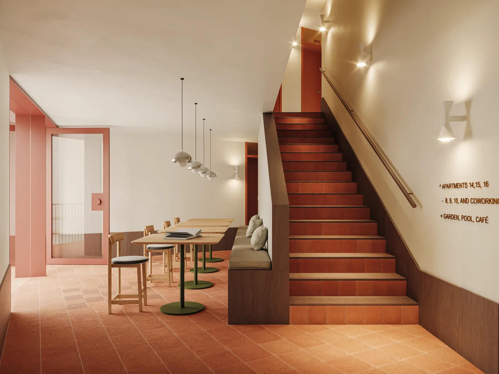 The shared workspace at the foot of the main stair: terracotta treads with timber nosings, a dark wood dado following the flight up, wayfinding letters on the wall and a work table with stools below.